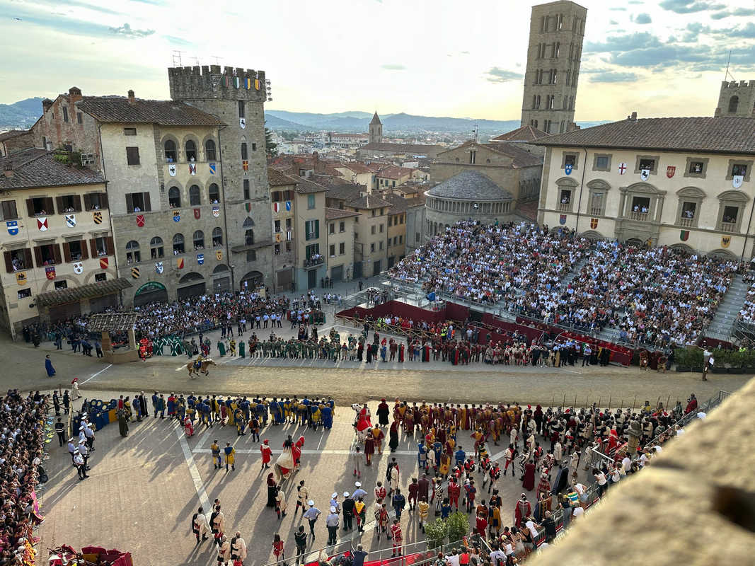 Panoramica di Piazza Grande durante la Giostra del Saracino, tra figuranti, pubblico e scorcio della città
