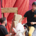 Cavaliere e addetto accanto a un cavallo bianco durante le prove