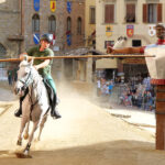 Giostratore in verde prepara la carriera su un cavallo bianco