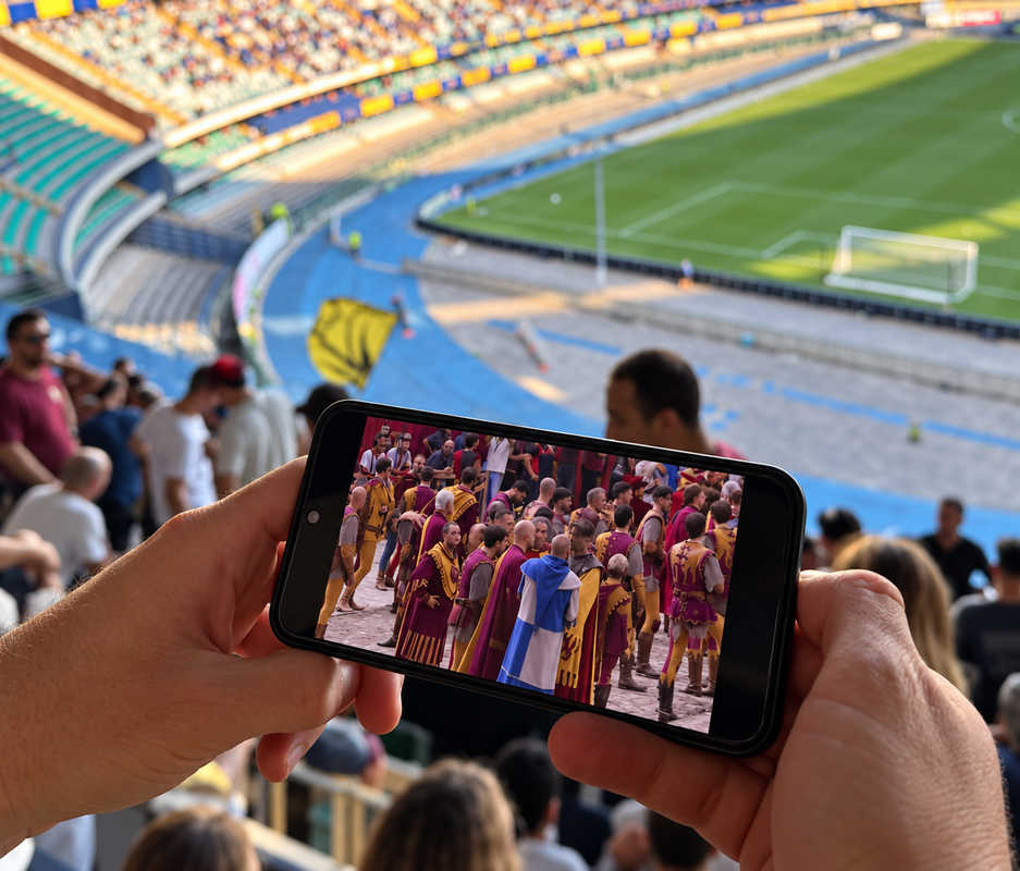 Tifoso amaranto allo stadio Bentegodi di Verona guarda la Giostra del Saracino di Arezzo sul telefono durante Verona-Arezzo